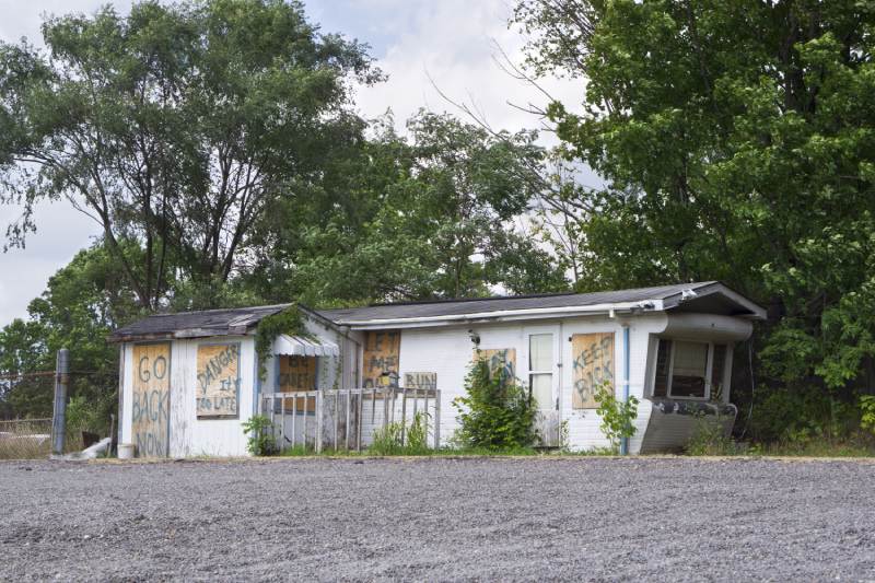 A dilapidated mobile home boarded up and covered with graffiti.