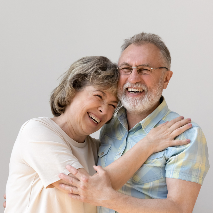 Sincere laughing bonding happy middle aged senior married couple cuddling, having fun enjoying communicating, isolated on white wall, showing candid loving feelings, good family relations concept.