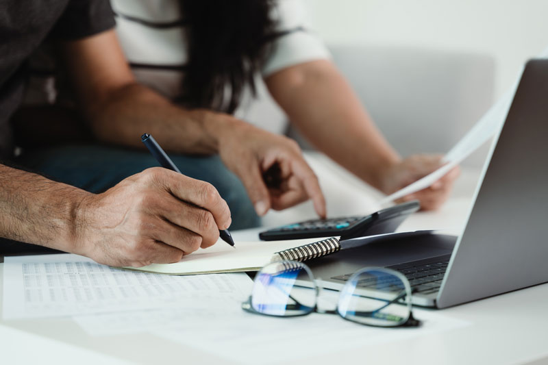 photo of a man and woman with a pen, and calculator signifying computation of tax on a sale of an inherited mobile home